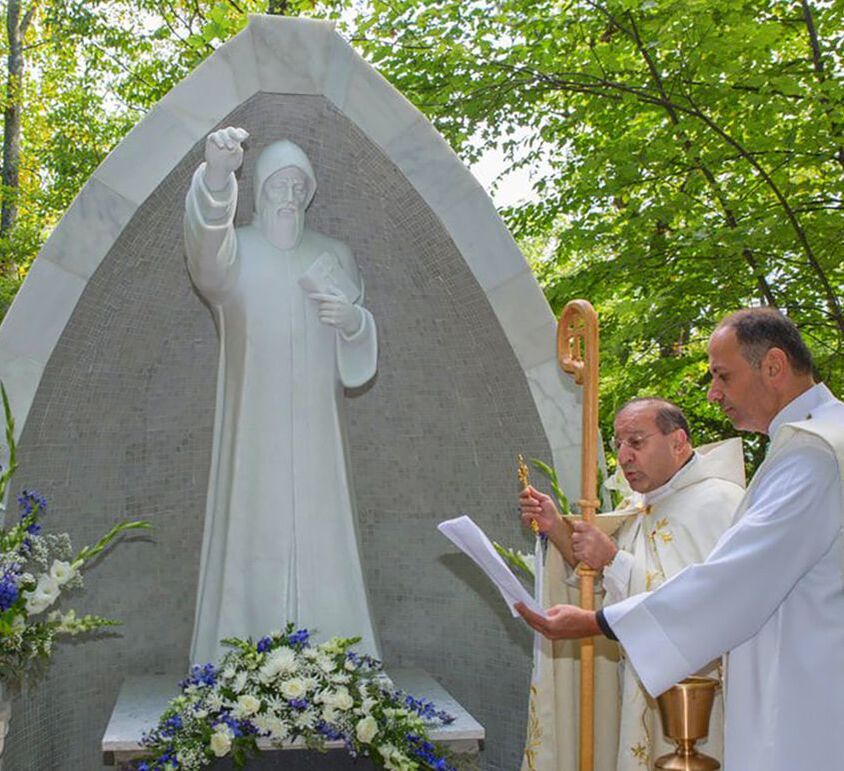 Two priests prayer infront of the statue of Saint Sharbel during St. Sharbel's Shrine Dedication at the National Shrine Grotto in Maryland